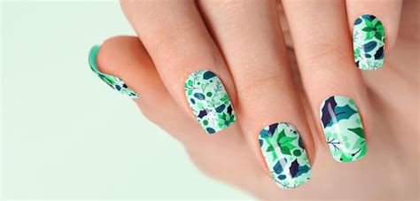 Mão lindas unhas verdes escuras em tons de nude padrões florais Foto Premium