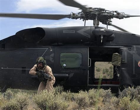 Navy personnel in a HH-60H Seahawk helicopter move in with M-4 Carbine at the ready to extract ...