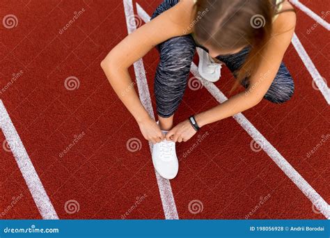 Top View On Female Runner Tying Shoelaces On The Running Track Stock