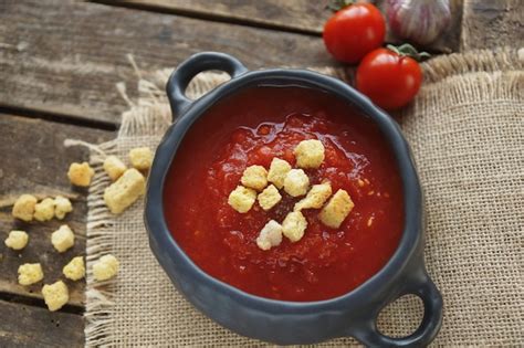 Premium Photo Bowl Of Tomato Soup With Crackers And Clove On Rustic Wooden Table