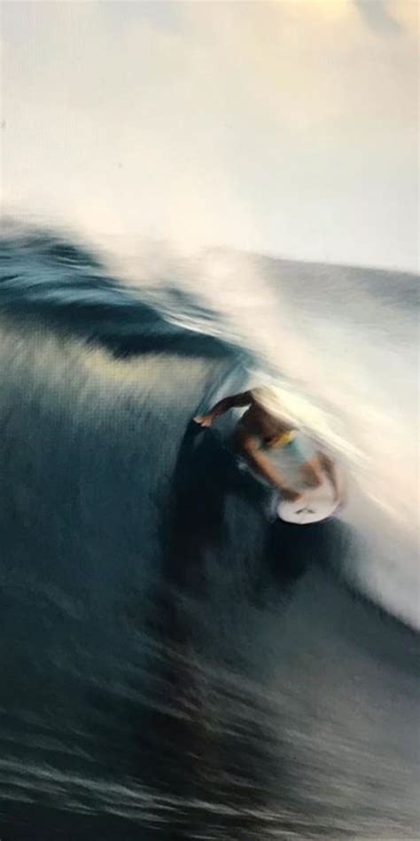 A Man Riding A Wave On Top Of A Surfboard