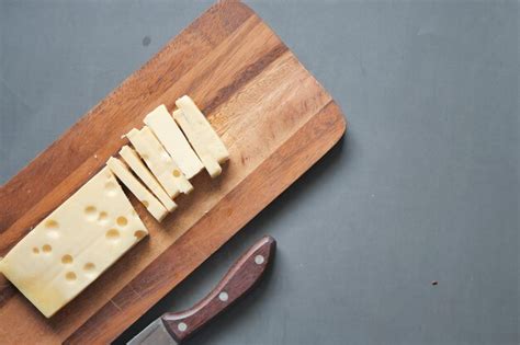 Queso En Lonchas Con Agujeros En Una Tabla De Cortar En La Mesa Foto