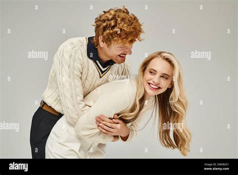 Cheerful Redhead Man Hugging Excited Blonde Woman And Having Fun On Grey Backdrop Classic