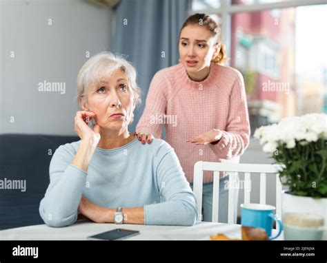 Adult Daughter Calming Upset Mother After Quarrel At Table Stock Photo