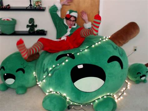 A Man In Elf Costume Sitting On Top Of A Green Stuffed Animal With