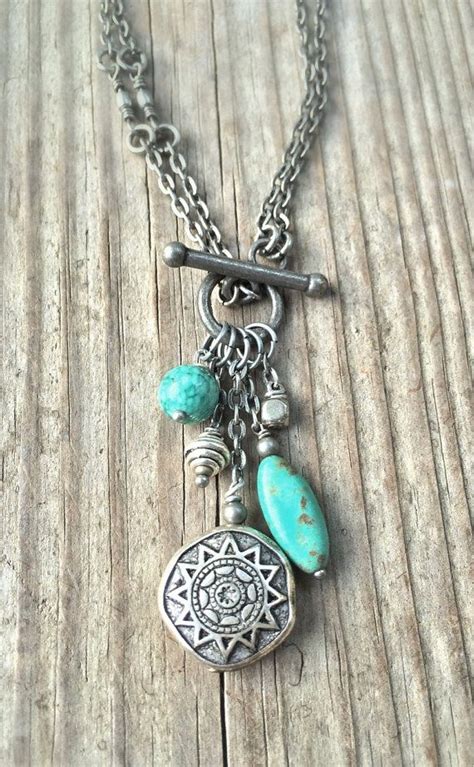 a necklace with turquoise beads and charms hanging from it on a wooden ...