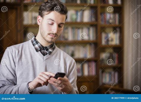 Homem Novo Atrativo Que Datilografa No Telefone Celular Interno Imagem