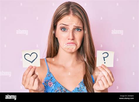 Jeune fille blonde tenant le coeur et le point d interrogation rappel déprimé et s inquiéter de