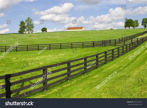 Sprawling Acres Of Fenced In Green Pastures Surround A Horse Farm Ranch