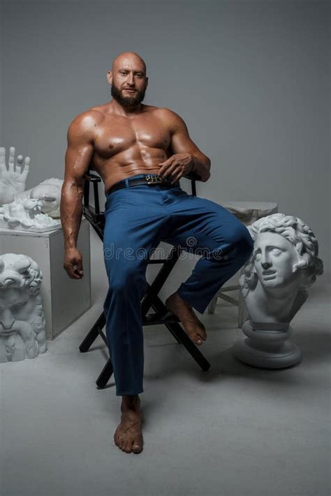 Seductive Muscular Man Sitting On Chair Around Marble Busts Stock Image