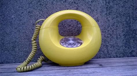 A Yellow Telephone Sitting On Top Of A Wooden Table Next To A Gray