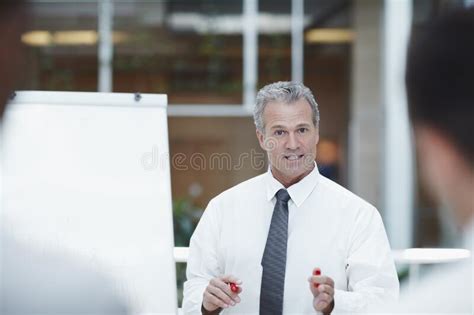 Leading The Team A Senior Businessman Standing Besides A Flipchart