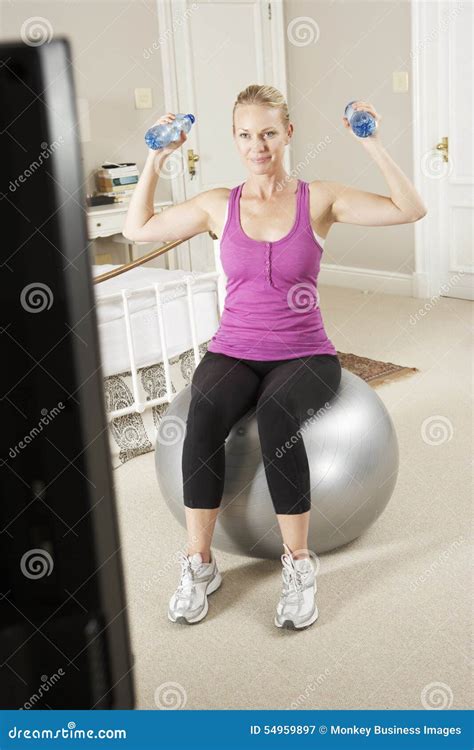 Woman Exercising Whilst Watching Fitness Dvd On Television Stock Image