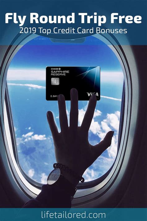 a person's hand holding up a credit card in front of an airplane window