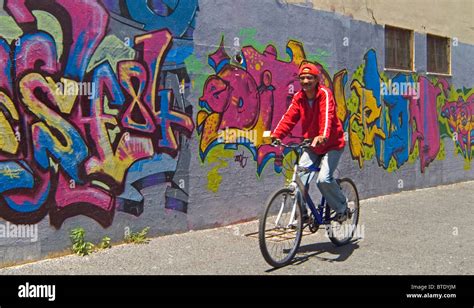 Un Sonriente Ciclista Paseos Pasado Una Pared Cubierta De Graffiti