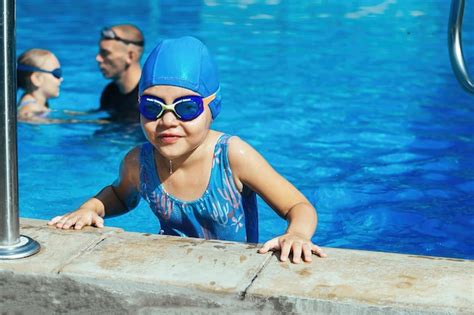 Une petite fille à des cours de natation dans une piscine extérieure