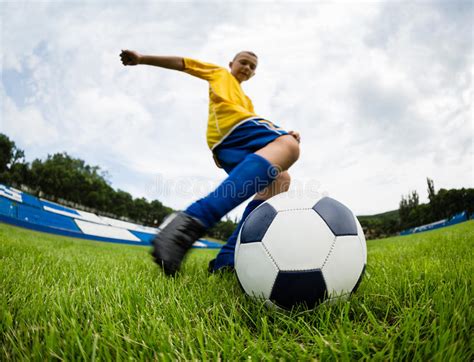 El Jugador De F Tbol Del Muchacho Golpea La Bola Del F Tbol Imagen De