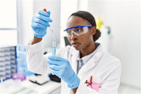 African American Woman Scientist Pouring Liquid On Test Tube At