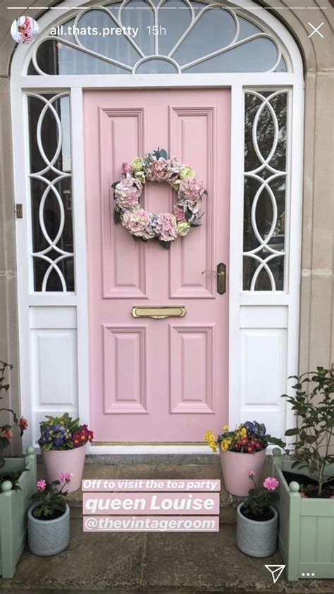 A Pink Front Door With Potted Plants And Flowers On The Steps To An