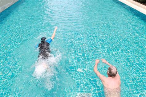 Side View Image Of Happy Elderly Asian Swimming In Pool During Retirement Holiday With