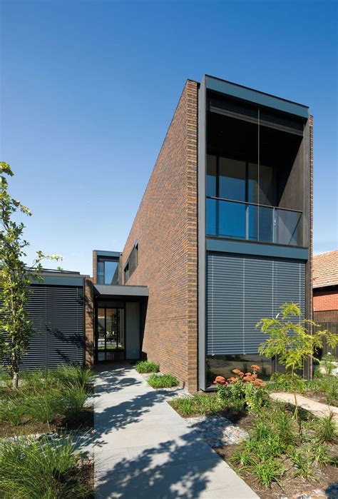 The House Is Made Out Of Brick And Has Many Plants Growing In Front Of It