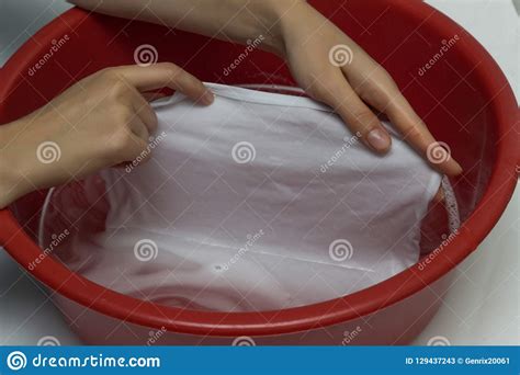 The Girl Erases A Children`s White T Shirt In A Red Basin From Stains