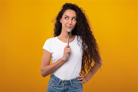 Retrato De Una Dama Latina Sonriente Sosteniendo Un Tenedor En La Boca Foto Premium