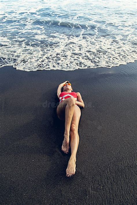 Caucasian Woman Beautiful And Sexy In A Bikini Lying On The Black Sandy Beach At The Seashore
