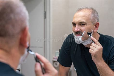 Middle Aged Handsome Man Shaving His Beard In Bathroom Stock Image