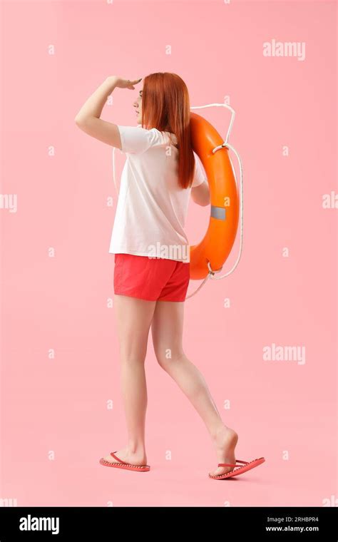 Female Lifeguard With Ring Buoy On Pink Background Back View Stock