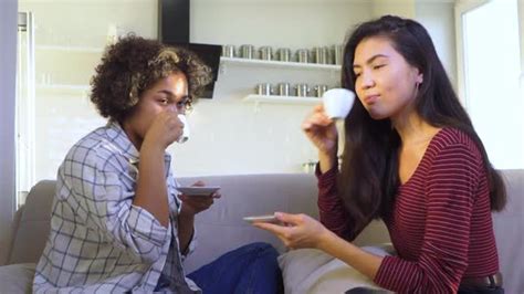 Two Girlfriends Gossiping While Sitting On The Couch Stock Footage