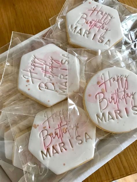 Four Decorated Cookies Sitting On Top Of A Plastic Bag Covered In Pink