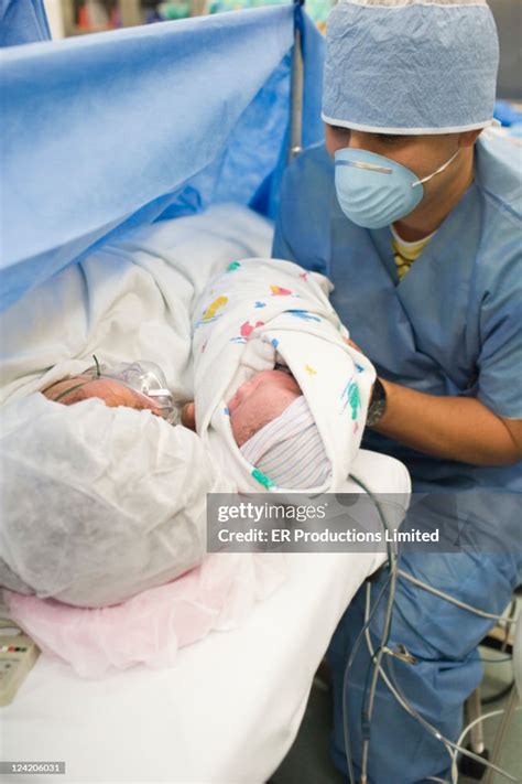 Father Showing Newborn Baby Girl To Mother In Operating Room High Res