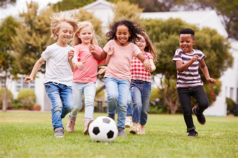 Group Of Children Playing Football With Friends In Park Stock Photo ...