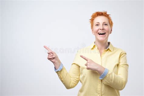Surprised Funny Mature Woman In Yellow Shirt Showing Empty Copy Space