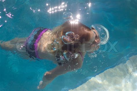 A Young Girl Is Resurfacing In A Swimmingpool From A Dive While