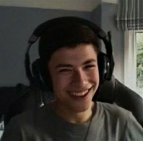 A Young Man Wearing Headphones And Smiling At The Camera While Sitting In Front Of A Window