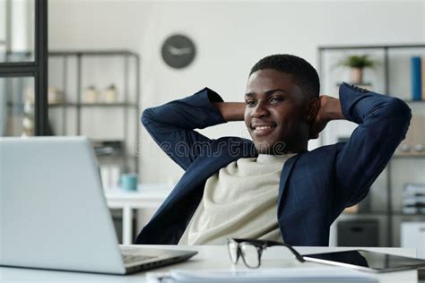 Young Restful Businessman Keeping Hands Behind Head And Looking At