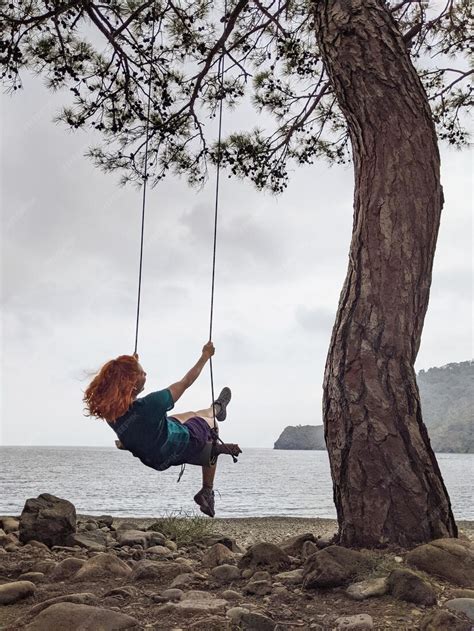 Premium Photo A Girl Swings On A Swing On A Tree Near A Lake