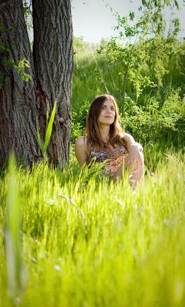 Premium Photo Portrait Of Beautiful Woman Sitting By Trees On Grassy