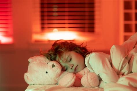 Niño disfrutando de dulces sueños niño durmiendo en la cama con un oso