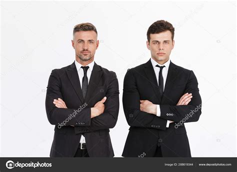 Image Of Masculine Serious Two Businessmen In Office Suits Looking At