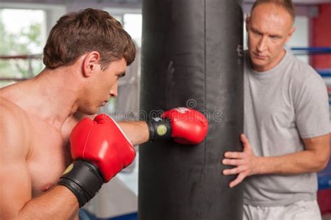 O Pugilista E O Seu Treinam Fazer Algum Que Perfura Saco Foto De