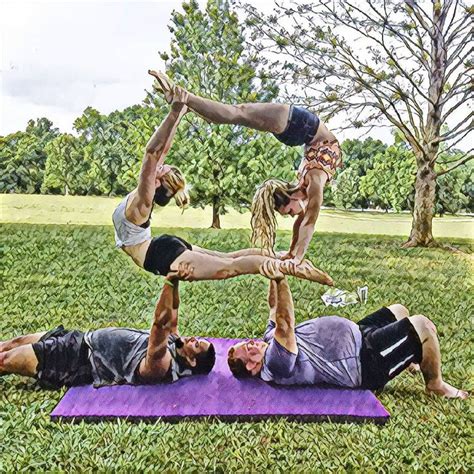 Three People Doing Handstands On A Purple Yoga Mat In The Middle Of A Park