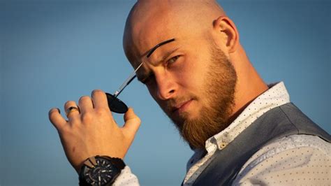 Premium Photo Bold Guy With A Stylish Beard And Sunglasses On A Sky Surface During Sunset