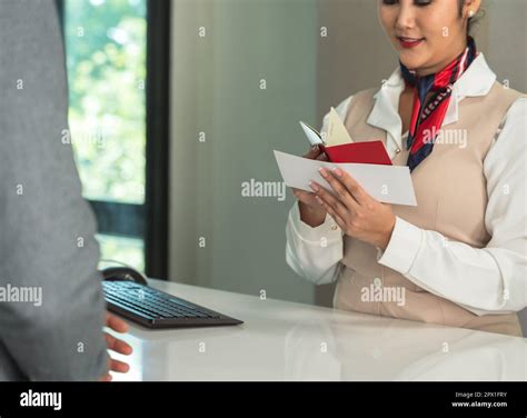 Female Flight Attendant Checking Passport And Boarding Pass At Airport