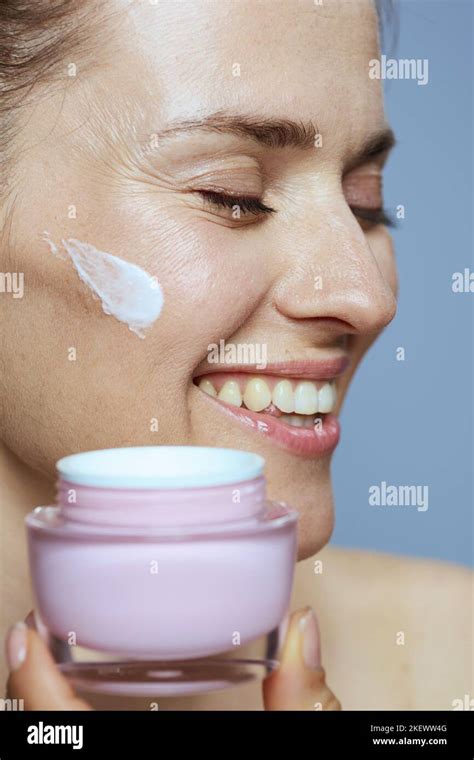 Happy 40 Years Old Woman With Cosmetic Cream Jar Isolated On Blue