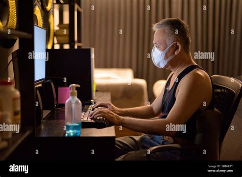 Mature Japanese Man With Mask Working Overtime At Home Stock Photo Alamy