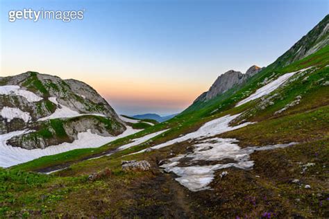 The Snowdrifts And Green Grass On Top Of Mountains In The Tropical