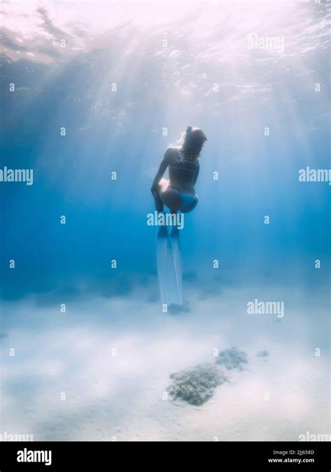 Woman Freediver In Bikini Posing Underwater Over Sandy Sea Bottom With